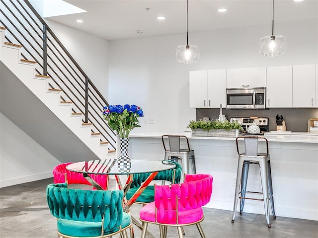 dining area with recessed lighting, concrete flooring, baseboards, and stairway