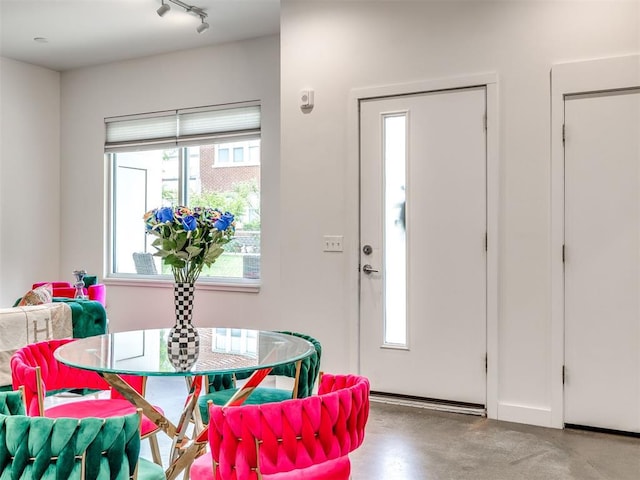 dining space with track lighting and finished concrete floors