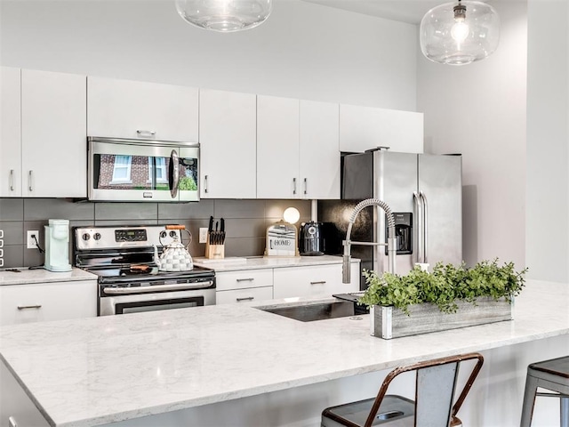 kitchen featuring appliances with stainless steel finishes, a sink, a kitchen breakfast bar, and decorative light fixtures