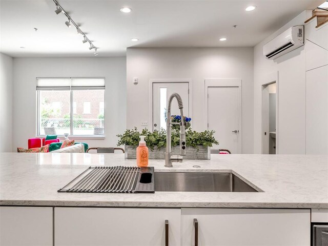 kitchen with a wall unit AC, track lighting, white cabinetry, light stone counters, and recessed lighting