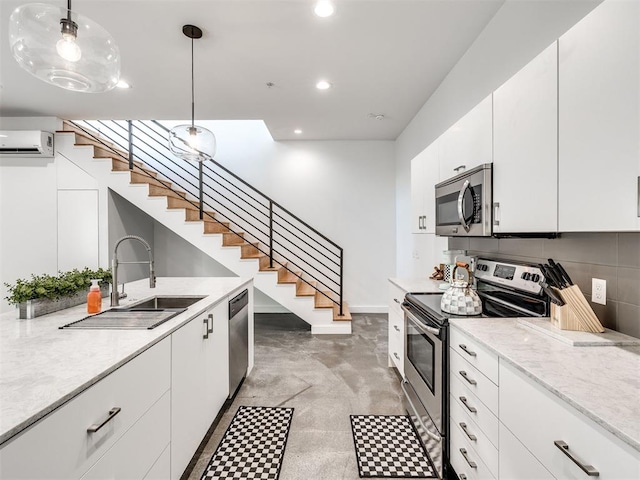 kitchen with stainless steel appliances, a wall unit AC, a sink, recessed lighting, and white cabinets
