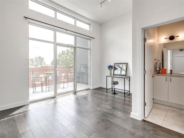 interior space featuring track lighting, wood finished floors, and baseboards