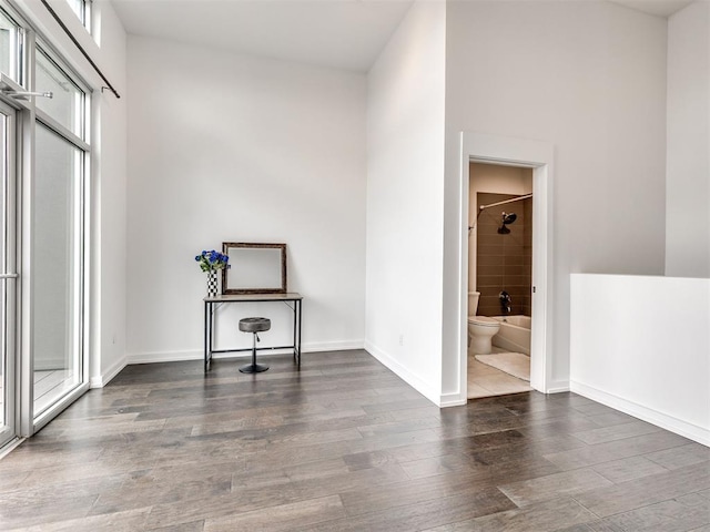 unfurnished bedroom with wood finished floors, baseboards, and connected bathroom