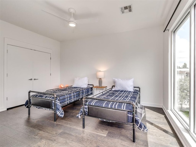 bedroom with multiple windows, wood finished floors, baseboards, and ceiling fan