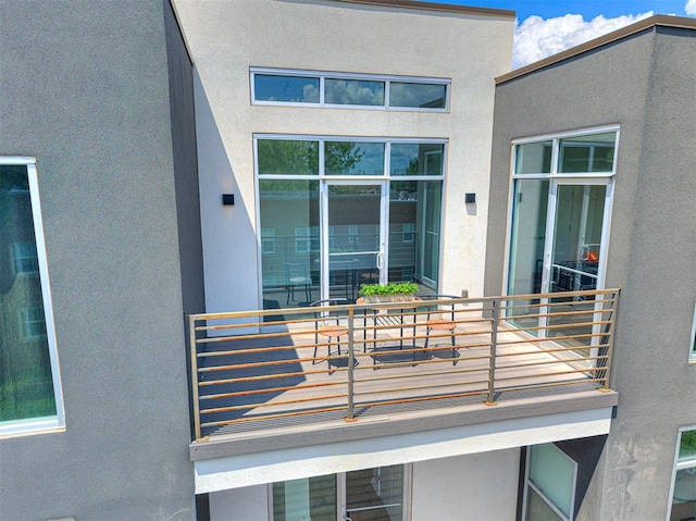property entrance with a balcony and stucco siding