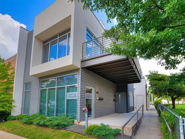 view of front of house featuring stucco siding and a balcony