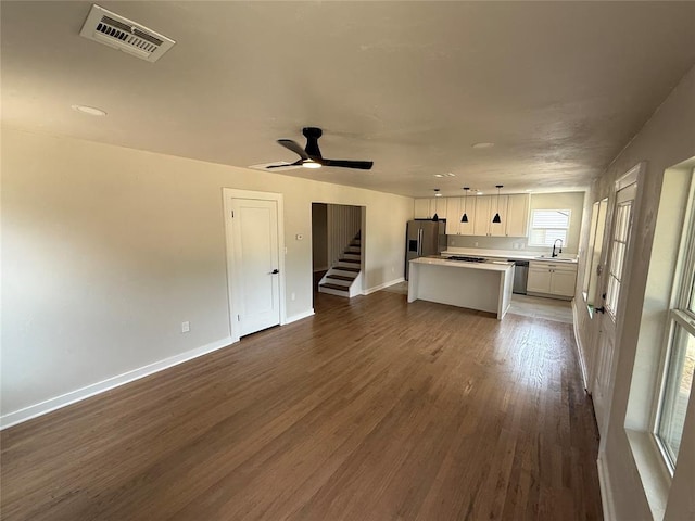 1212 NW 48th St, Oklahoma City, OK 73118 - unfurnished living room featuring a sink, dark wood finished floors, baseboards, a ceiling fan, and stairway