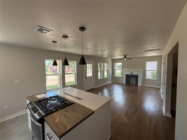 1212 NW 48th St, Oklahoma City, OK 73118 - kitchen featuring stainless steel range with gas stovetop, baseboards, a fireplace, pendant lighting, and dark wood-style floors
