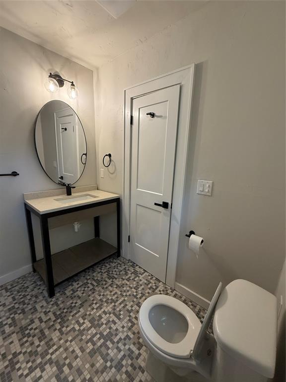 1212 NW 48th St, Oklahoma City, OK 73118 - bathroom with toilet, a sink, and baseboards