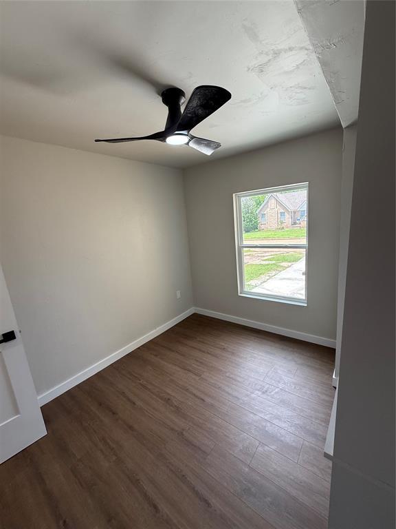 1212 NW 48th St, Oklahoma City, OK 73118 - spare room featuring a ceiling fan, dark wood-style flooring, and baseboards