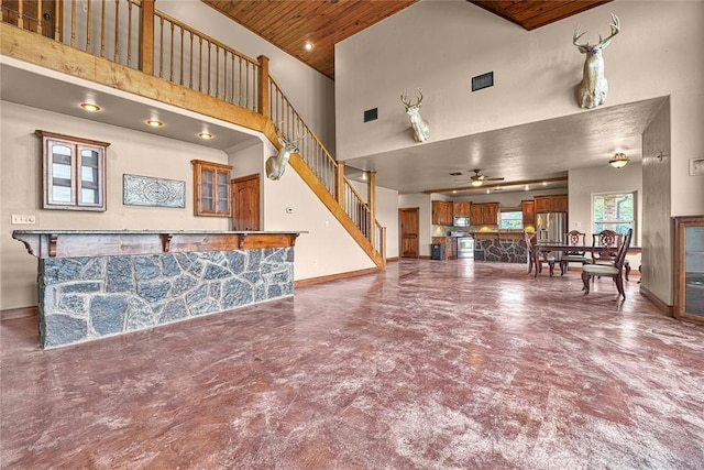 21698 SW Coombs Rd, Cache, OK 73527 - unfurnished living room with a towering ceiling, finished concrete floors, wood ceiling, stairway, and baseboards
