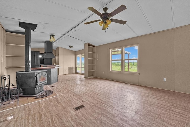 21698 SW Coombs Rd, Cache, OK 73527 - unfurnished living room featuring a wood stove, lofted ceiling, ceiling fan, and wood finished floors