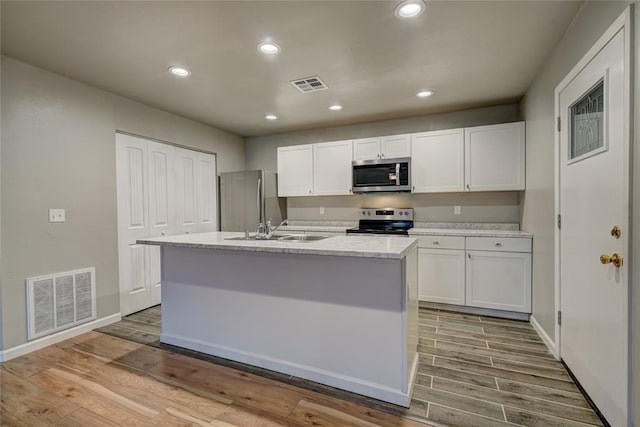 403 S Debra Ct Unit 401, Stillwater, OK 74074 - kitchen featuring appliances with stainless steel finishes, a sink, a kitchen island with sink, wood finished floors, and recessed lighting