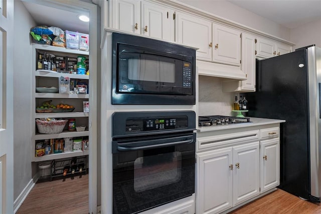 3804 NW 66th St, Oklahoma City, OK 73116 - kitchen with black appliances, light wood-style floors, white cabinetry, light countertops, and tasteful backsplash