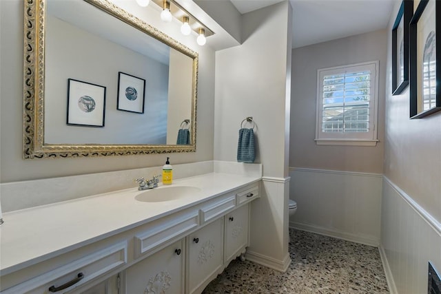 3804 NW 66th St, Oklahoma City, OK 73116 - bathroom featuring wainscoting, toilet, vanity, speckle patterned floor, and baseboards