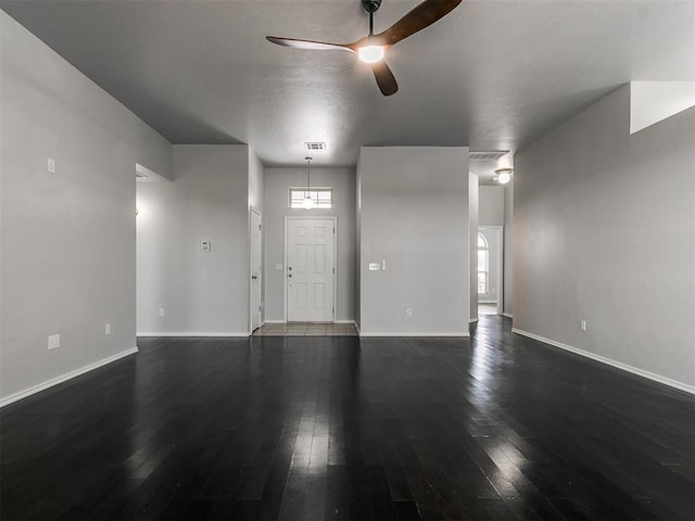 unfurnished living room featuring a ceiling fan, dark wood finished floors, and baseboards