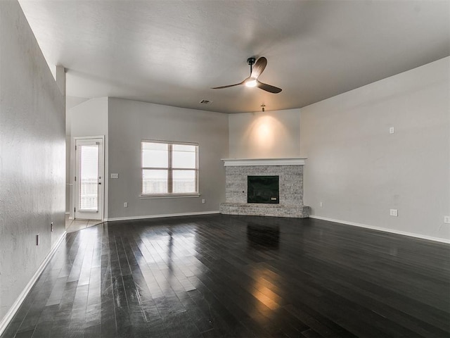 unfurnished living room with dark wood-style floors, ceiling fan, baseboards, and a fireplace with raised hearth
