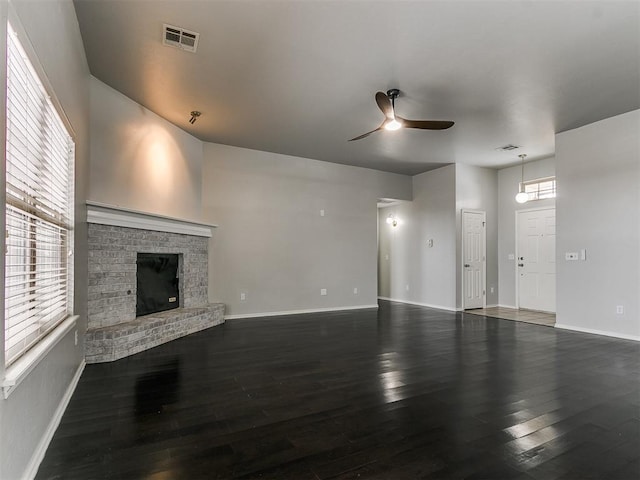 unfurnished living room featuring a ceiling fan, wood finished floors, baseboards, and a brick fireplace
