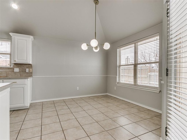 unfurnished dining area with vaulted ceiling, light tile patterned flooring, plenty of natural light, and a chandelier