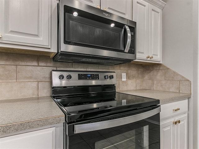 kitchen with stainless steel appliances, white cabinets, light countertops, and backsplash