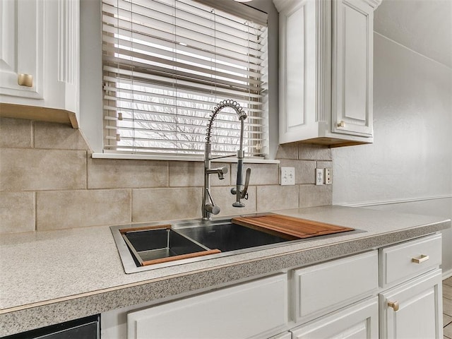 kitchen with a sink, decorative backsplash, light countertops, and white cabinetry