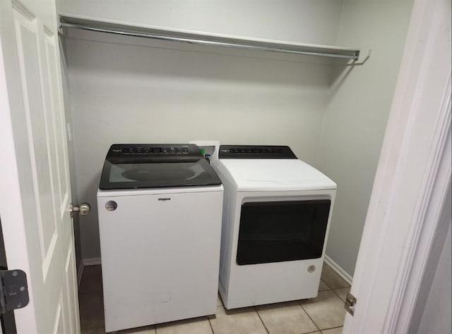 clothes washing area with washing machine and dryer and light tile patterned flooring