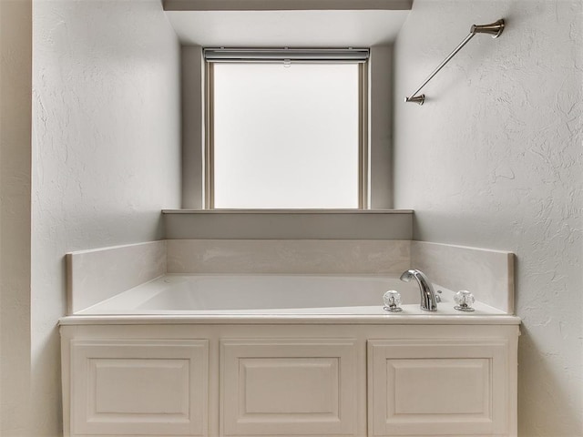 bathroom with a garden tub and a textured wall