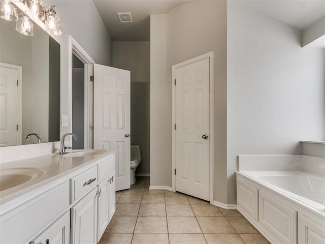 bathroom with toilet, tile patterned flooring, a garden tub, double vanity, and baseboards