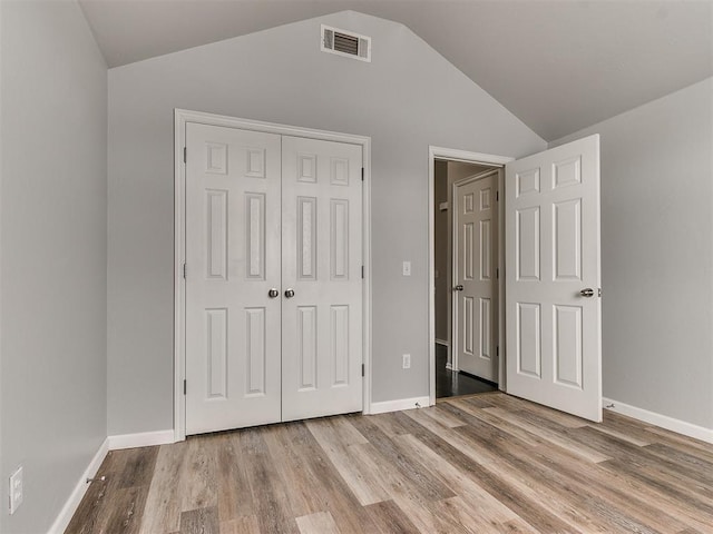 unfurnished bedroom with vaulted ceiling, a closet, wood finished floors, and baseboards