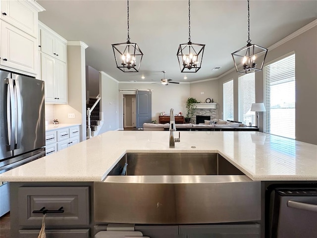 kitchen with stainless steel appliances, a sink, a chandelier, open floor plan, and crown molding