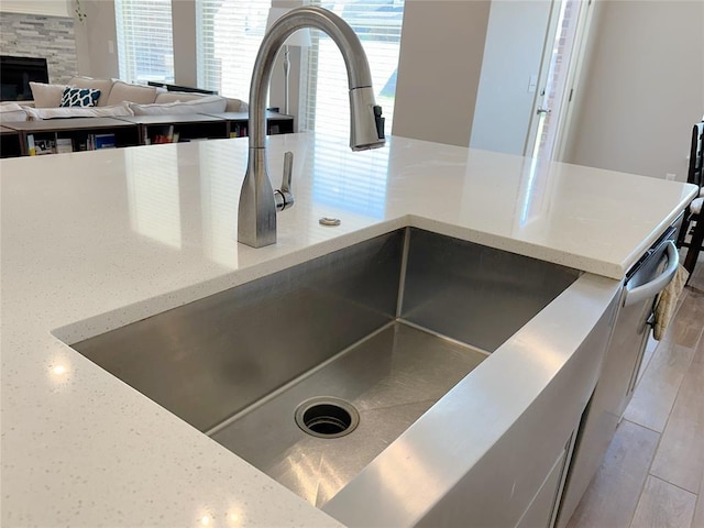 kitchen view of a sink, light wood-type flooring, and light stone countertops