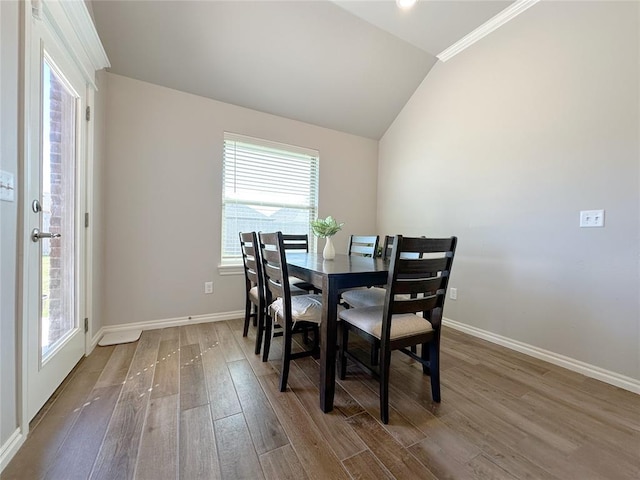 dining space featuring wood finished floors, baseboards, and lofted ceiling