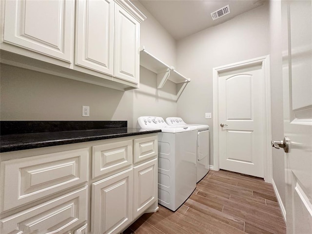 laundry room featuring washer and dryer, light wood-type flooring, cabinet space, and baseboards