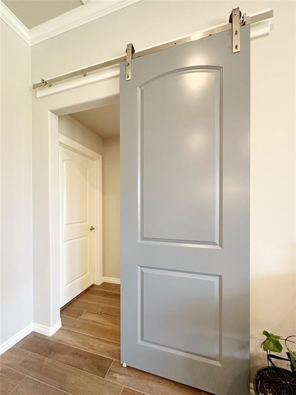 detailed view of a barn door, wood finished floors, ornamental molding, and baseboards