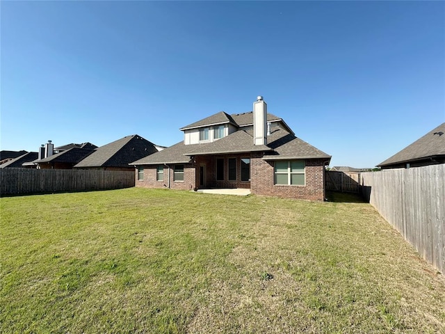 back of property with a chimney, brick siding, a patio area, and a shingled roof