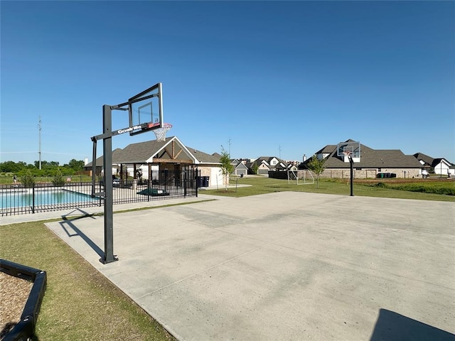 view of sport court featuring community basketball court, fence, and a residential view