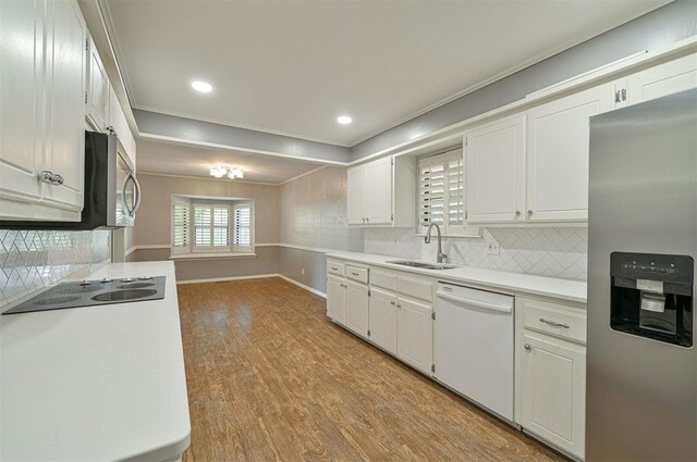 8720 Raven Ave, Oklahoma City, OK 73132 - kitchen with stainless steel appliances, a sink, white cabinets, light countertops, and light wood-style flooring