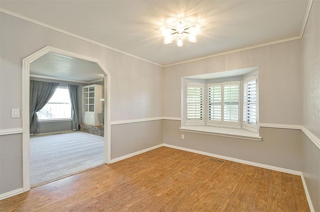 8720 Raven Ave, Oklahoma City, OK 73132 - empty room featuring wood finished floors, baseboards, ornamental molding, a chandelier, and arched walkways