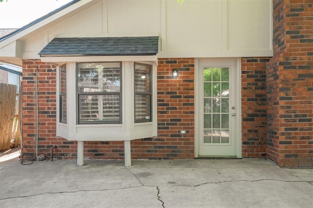 8720 Raven Ave, Oklahoma City, OK 73132 - view of exterior entry featuring brick siding, fence, roof with shingles, and a patio area