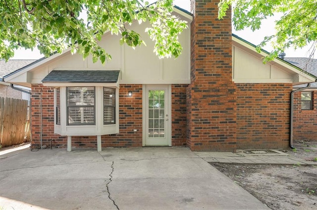 8720 Raven Ave, Oklahoma City, OK 73132 - rear view of property featuring fence, a patio area, brick siding, and a chimney