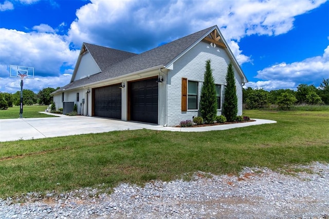 view of home's exterior featuring an attached garage, driveway, a yard, a shingled roof, and brick siding