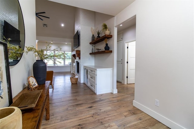 hallway with wood finished floors, baseboards, and a towering ceiling