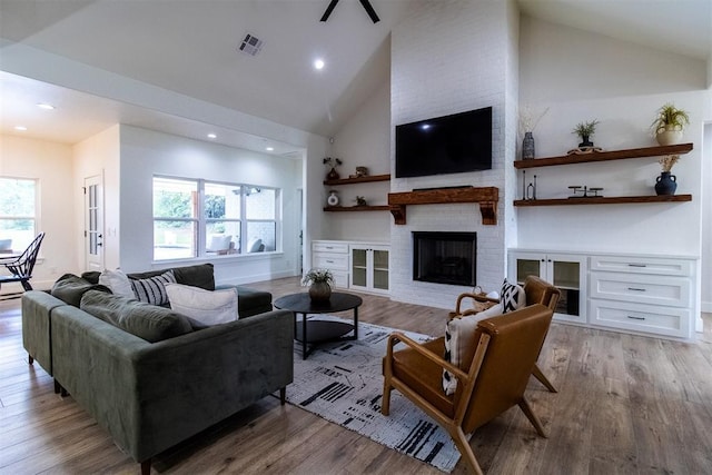 living area featuring a brick fireplace, light wood-type flooring, high vaulted ceiling, recessed lighting, and ceiling fan