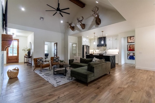 living room featuring light wood-type flooring, beam ceiling, a ceiling fan, recessed lighting, and high vaulted ceiling