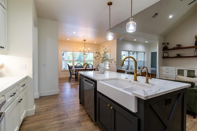 kitchen featuring stainless steel dishwasher, a sink, recessed lighting, light stone countertops, and light wood-style floors