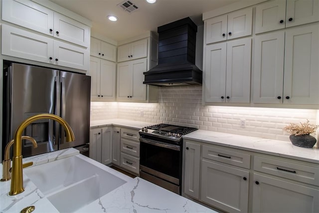 kitchen with stainless steel appliances, wall chimney exhaust hood, a sink, recessed lighting, and decorative backsplash
