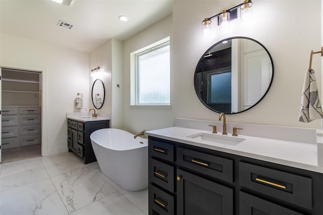 full bathroom with marble look tile flooring, a freestanding bath, two vanities, and a closet