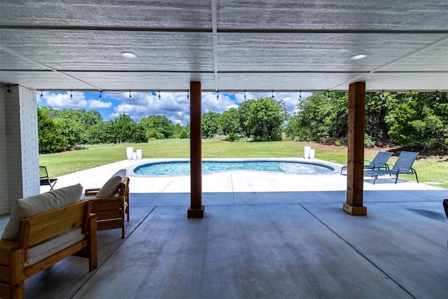 swimming pool with a patio area, a yard, and view of scattered trees