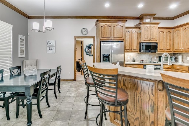 5608 Bent Creek Dr, Oklahoma City, OK 73135 - kitchen with stainless steel appliances, crown molding, decorative backsplash, a kitchen breakfast bar, and a chandelier