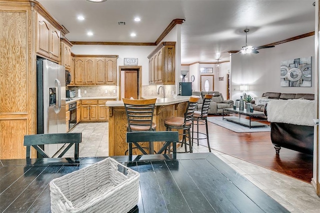 5608 Bent Creek Dr, Oklahoma City, OK 73135 - kitchen with stainless steel fridge, ornamental molding, a peninsula, open floor plan, and light countertops